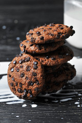oatmeal cookies with chocolate and milk on a dark wooden background