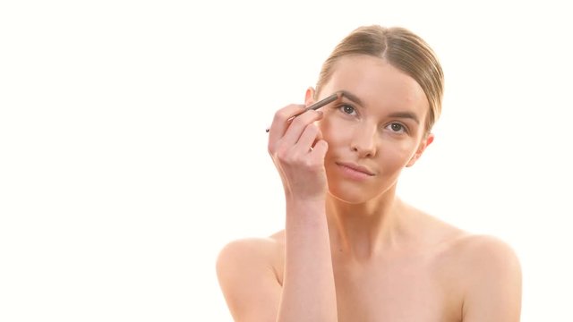 The woman applying makeup on her face on the white background