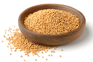 yellow mustard seeds in the wooden plate, isolated on white