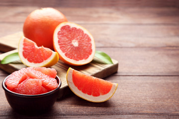 Ripe grapefruits slices in bowl on brown wooden table