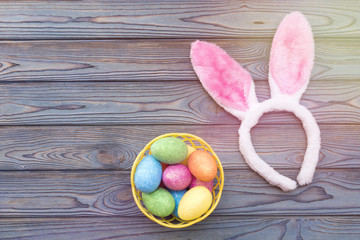 Easter eggs in a basket, ears of a hare on a wooden table background. celebration.