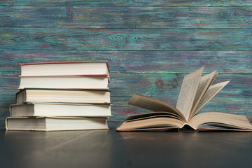 Open book hardback on Stack books on wooden background. Back to school with copy space.