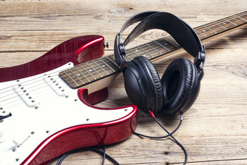 Electric guitar with headphones on wooden table.