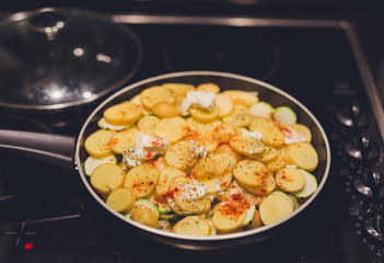 frying pan with potatoes, onions and zcchini recipe being cooked