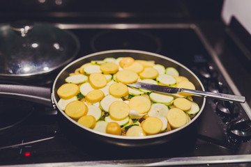 frying pan with potatoes, onions and zcchini recipe being cooked