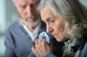 Close up portrait of tired senior woman with handkerchief and he