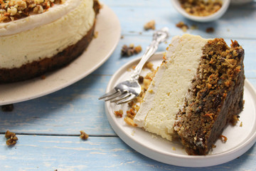 A piece of Carrot Cake Cheesecake on a white plate. Blue background, flat lay