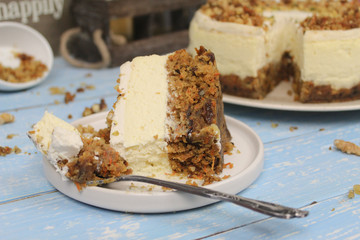 Piece of Carrot Cake Cheesecake on a white plate. Blue wooden background