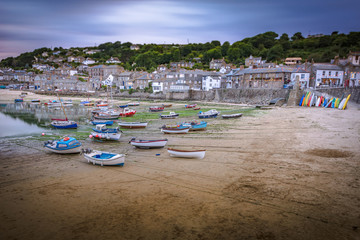 Boats resting on beach at the picturesque fishing village of Mousehole in Cornwall