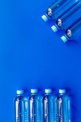 Drinking water in bottles on blue background top view copy space