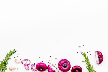 Red onion among spices rosemary, garlic, black peper on white background top view space for text