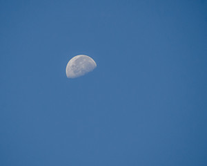 the half moon on the blue day sky
