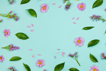 Flatlay frame floral background with daisies, wildflowers, petals and leaves, blue background. Copyspace