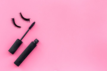 Basic products for eyelashes makeup. Mascara and false eyelashes on pink background top view copy space