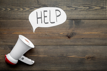 Call for help concept. Megaphone near cloud with word help on dark wooden background top view space...