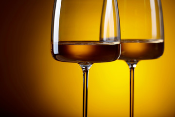 Glasses of white wine on a yellow background.