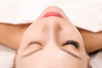 Eyelash Extension Procedure. Woman Eye with Long Eyelashes. Close up, selective focus.