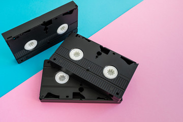 3 black VHS video tapes  a pink and blue background
