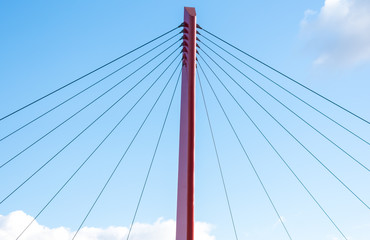 Close up on top of a red pillar and wires of a bridge.