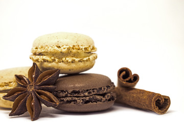 Vanilla and chocolate spicy macaroons with cinnamon sticks and anise on white background. French sweets.