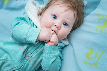 Funny baby lying on the bed.