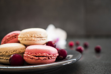 French dessert. Sweet pink macaroons or macarons with cranberry dark background