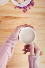 female hands holding coffee with milk on a wooden background