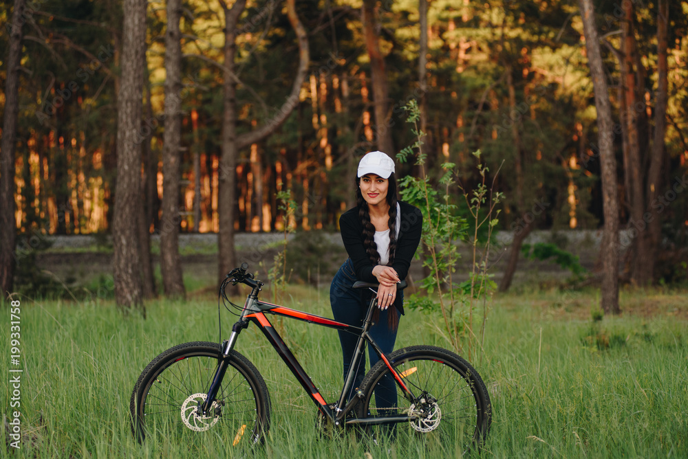 Wall mural bicyclist at the summer sunset on the desert road in the reserve territory. full length image of fem