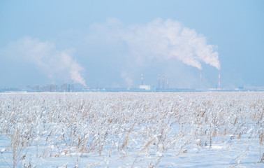 snowy field on a frosty winter day in the background smoking plant pipes, heavy frost sparkling snow