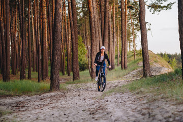 Naklejka premium Bicyclist at the summer sunset on the desert road in the reserve territory. Full length image of female bicycle. Extreme mountain bike sport athlete woman riding outdoors lifestyle trail