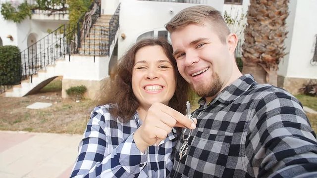 New homeowners with key selfie. Real estate, new house or apartment and people concept