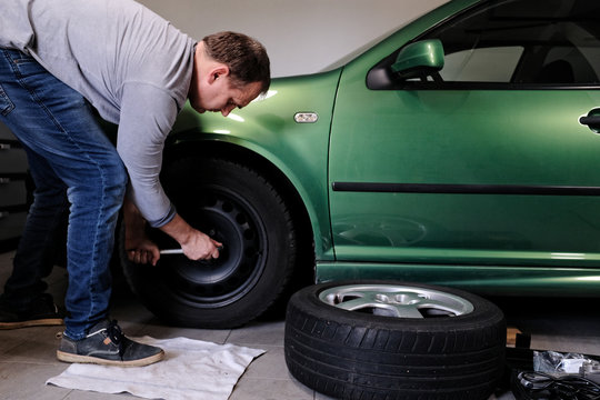 mann beim rad wechseln in der garage