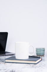 desktop with a laptop computer a journal a candle and a white mug