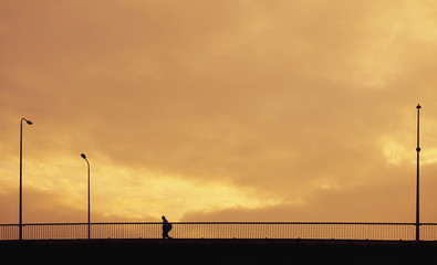 Fototapeta na wymiar Silhouette person does on bridge at sunset time in city. 