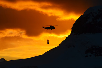 Sikorsky H-3 Helicopter flying at the Antarctica, heavy lift cargo. People working