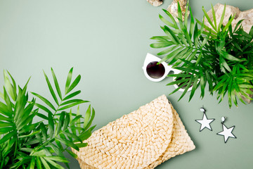 Tropical leaves and Beach bag with sunglasses  on  green  background. Top view, flat lay.