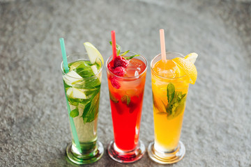 Cold fruit tea with apples, oranges and berries on the stone desk background