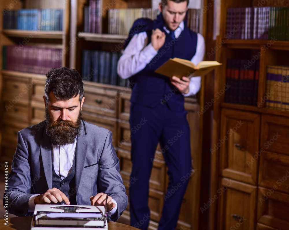 Fototapete man with beard typing on typewriter while his friend reading