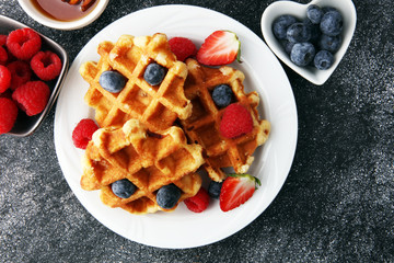 Traditional belgian waffles with fresh fruit and powder sugar on wooden board