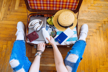 woman put clothes in suitcase while sit on floor. preparing for trip. travel concept