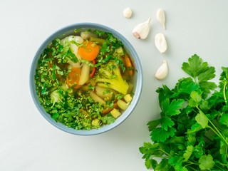 Healthy spring vegetable dietary vegetarian soup, gray concrete background, top view, close up.