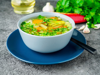Healthy spring vegetable dietary vegetarian soup, gray concrete background, side view, close up.