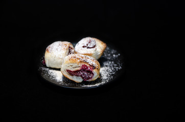 Cherry pies on the black plate on black background