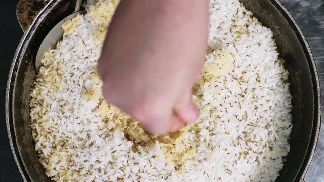 Close up shot of unrecognizable cook sprinkling rice pilaf with cumin seeds to put finishing touch to the dish, top view