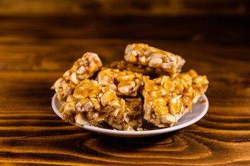 Ceramic plate with peanut brittles on wooden table.