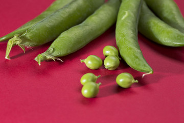 Green peas and pods on a red background