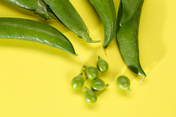 Green peas and pods on a yellow background