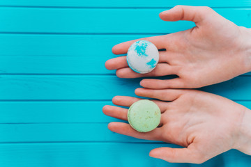 Macaroons or macarons lie in female hands on a turquoise background. Top view, copy space