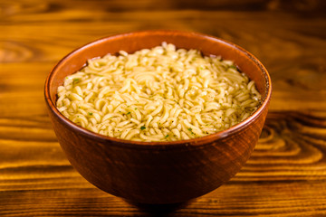 Ceramic bowl with prepared instant noodles on wooden table