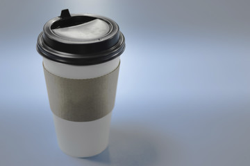 white paper Cup with black coffee lid with clean label for your text behind blue blurred background